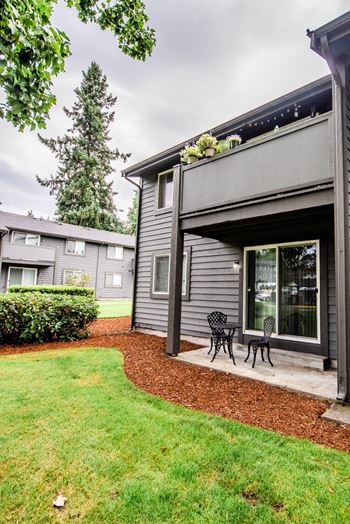 the back of a gray house with a patio with two chairs at Aero Apartments, Tacoma, WA, 98444